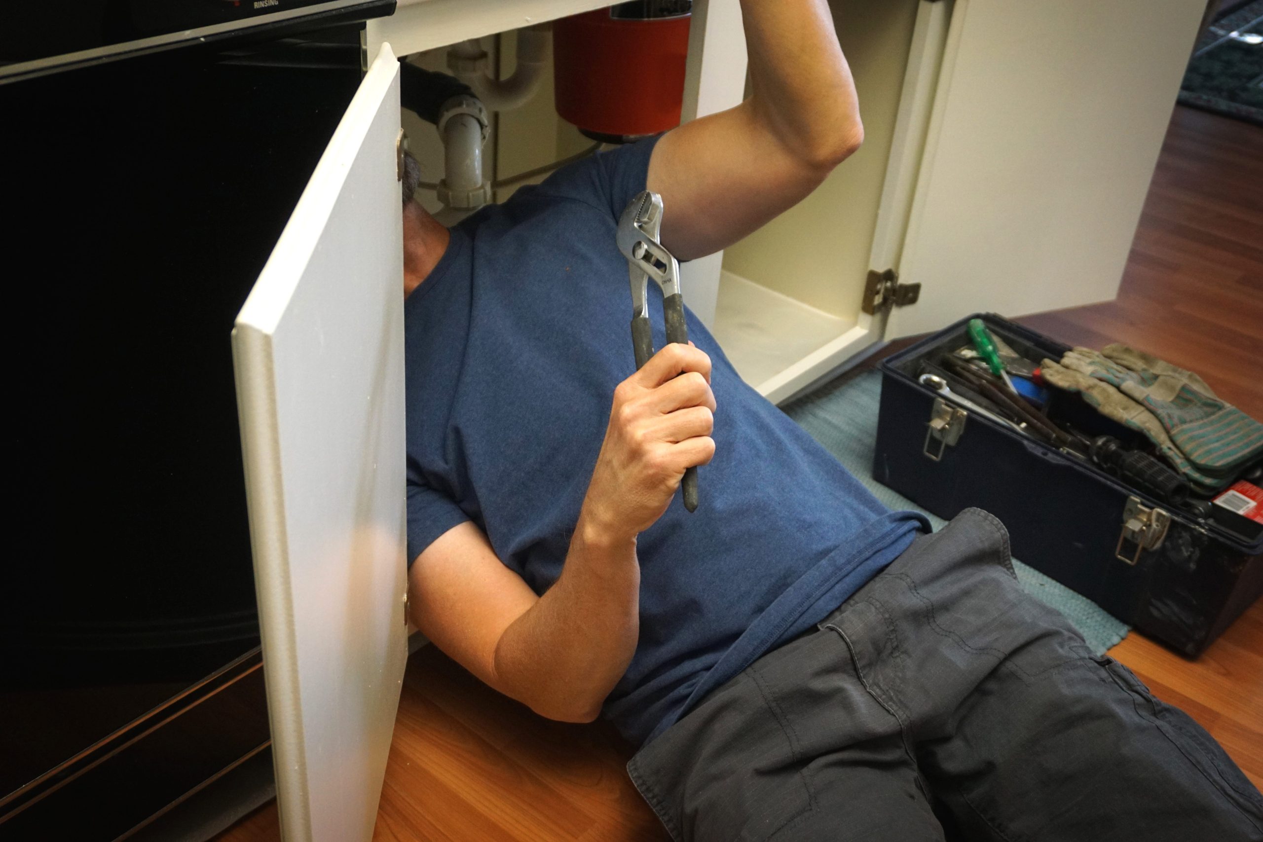 homeowner under the sink checking drain